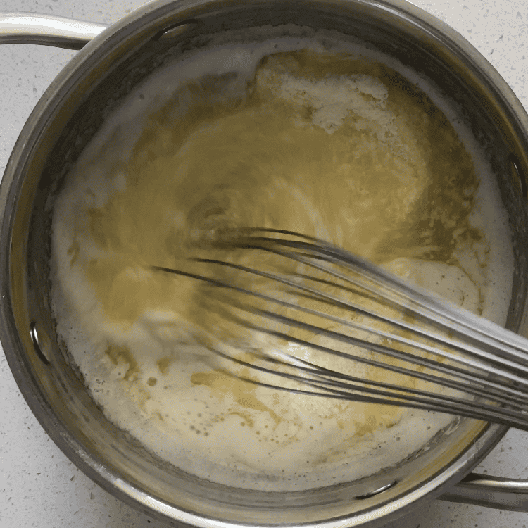 Melted butter and milk powder being whisked together in a medium saucepan.